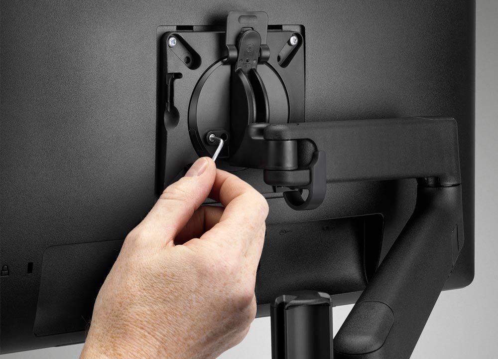 Monteur die een monitorarm monteert in een modern kantoor